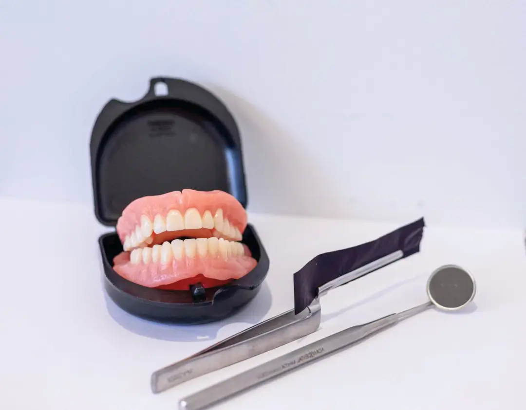 Dentures in a sleek case are accompanied by precision dental tools on a pristine white surface, showcasing the expertise of a premier Gold Coast denture clinic.