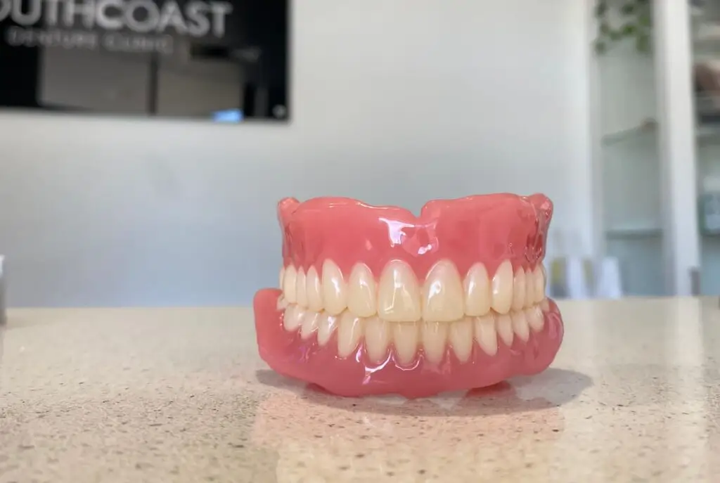 A set of dentures rests on the countertop in a bustling denture clinic's office.