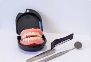 Dental prosthetics from Palm Beach Dentures, complete with tools and an open case on a white background.
