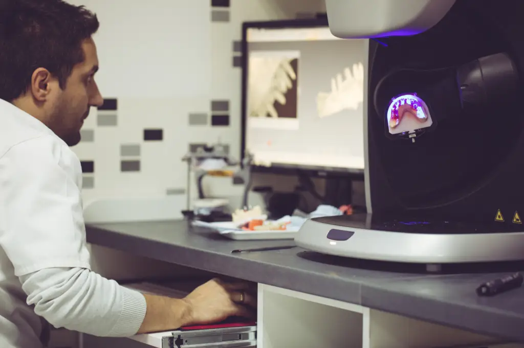 A person is analyzing a dental scan on the computer with a 3D model, exploring the nuances between digital dentures and traditional dentures in the dental lab.