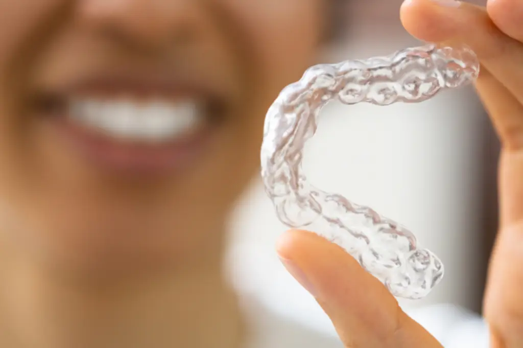 A person grinning in the background holds a mouthguard