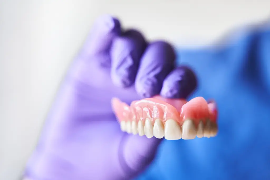 A gloved hand holds a digital dentures