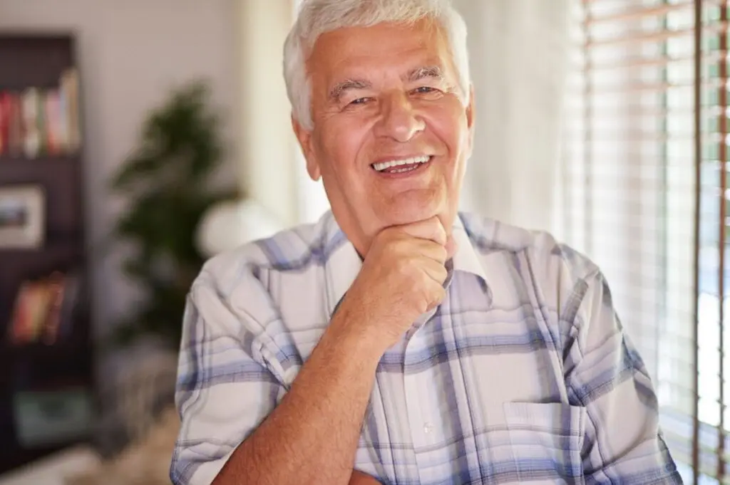 Elderly man smiling, in plaid shirt, happy with his Immediate Dentures.