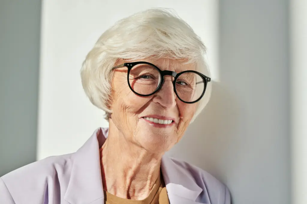 Elderly person with glasses and a smile, showcasing implant-supported dentures.