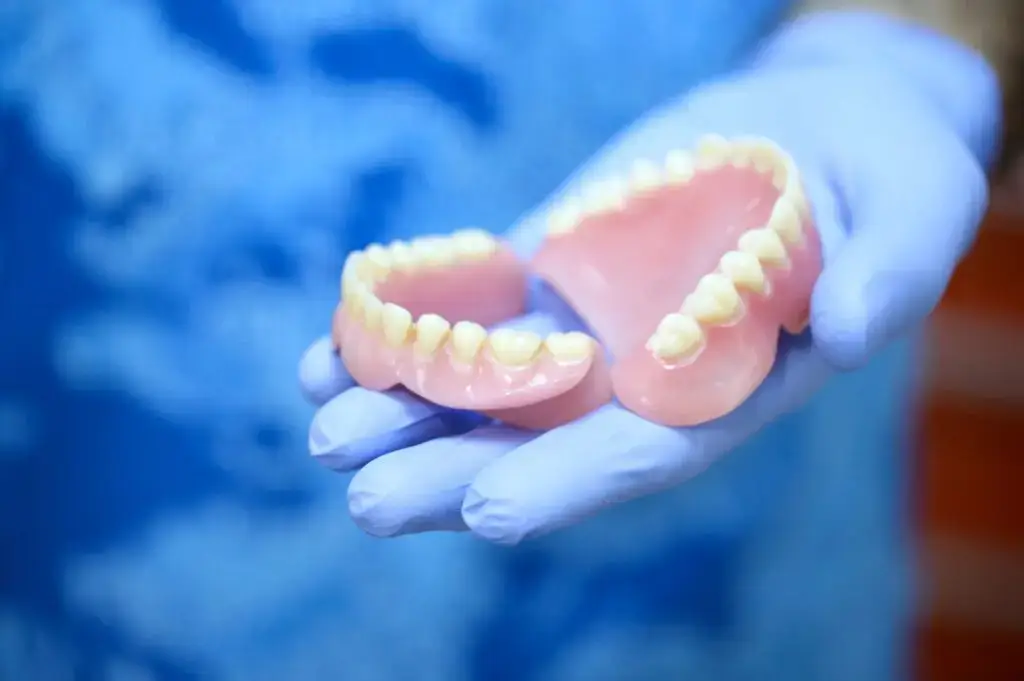 a dentists showing a set of complete dentures and explaining how other tooth replacement solutions is right for you