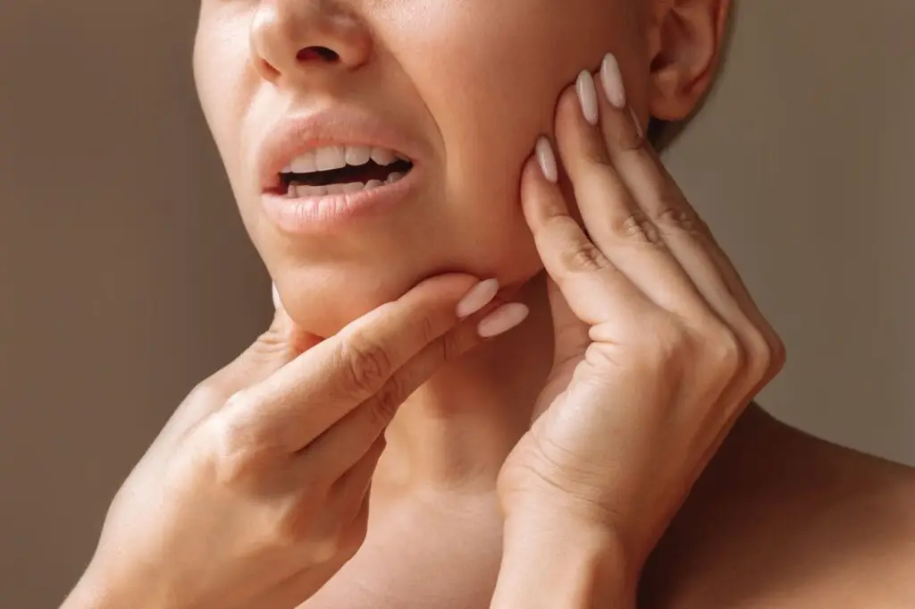 A woman with her hands on her chin, reflecting on how dentures affect jaw bone health and overall well-being.