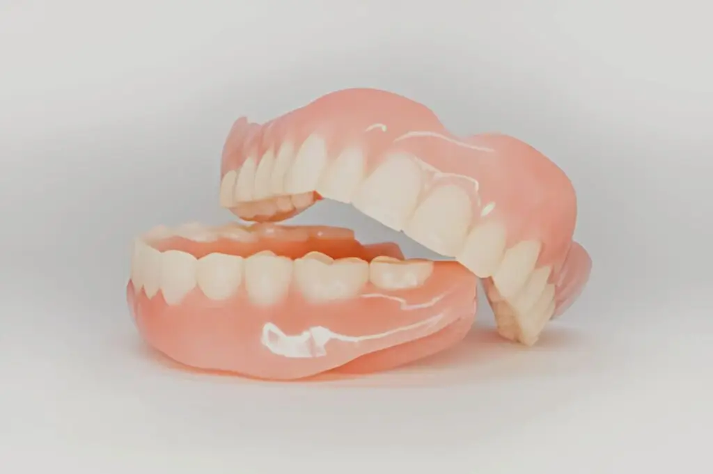 A set of upper and lower dentures, ideal for adjusting to complete dentures, on white background.