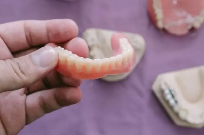 Close-up of a person holding a denture, highlighting maintenance tips for Valplast dentures.