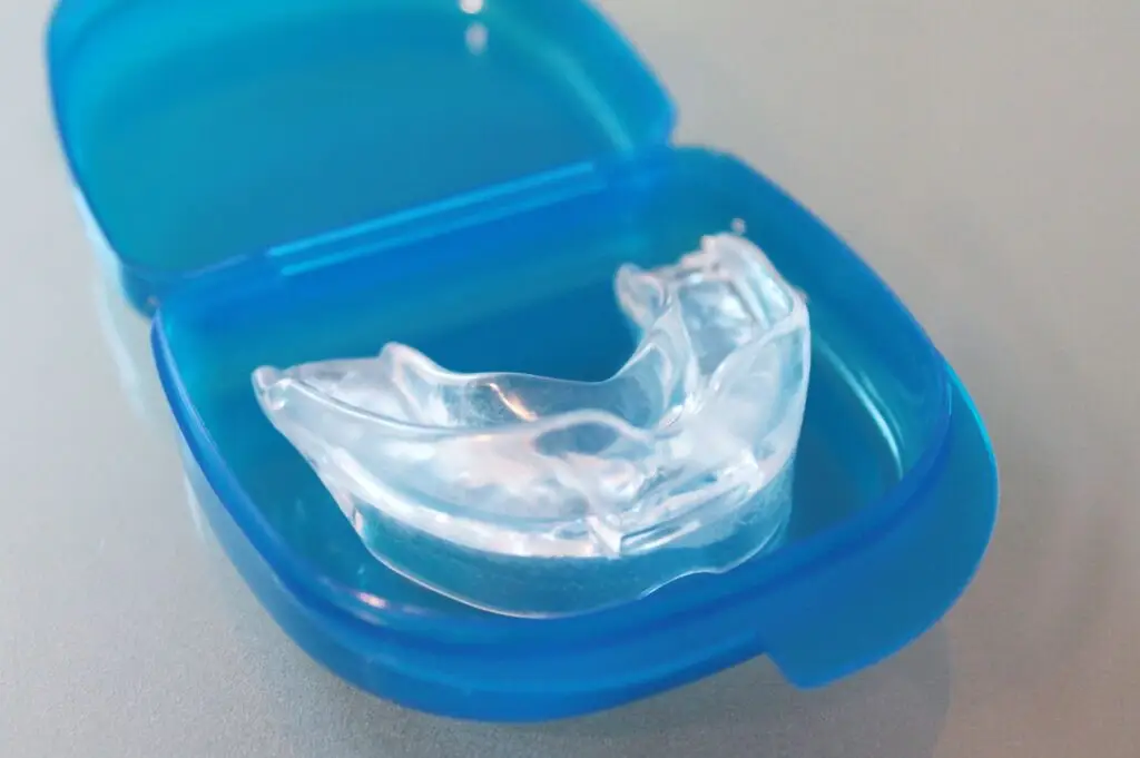 A clear custom mouthguard in a blue plastic case.