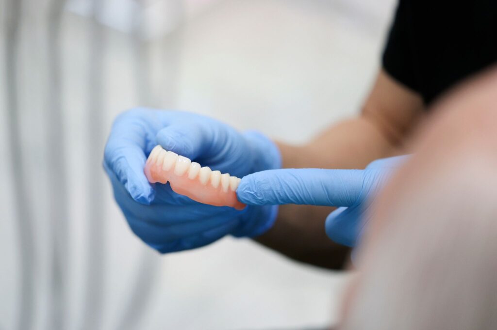 Gloved hands holding dentures, illustrating how often should dentures be relined.