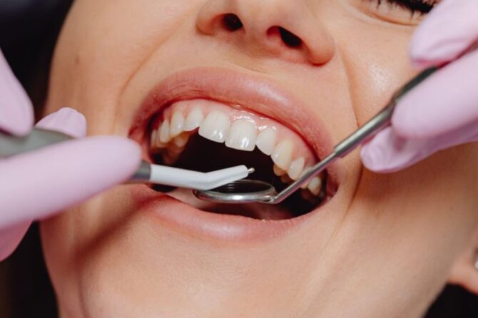 Close-up of a person receiving a dental check-up with dental tools in their mouth.
