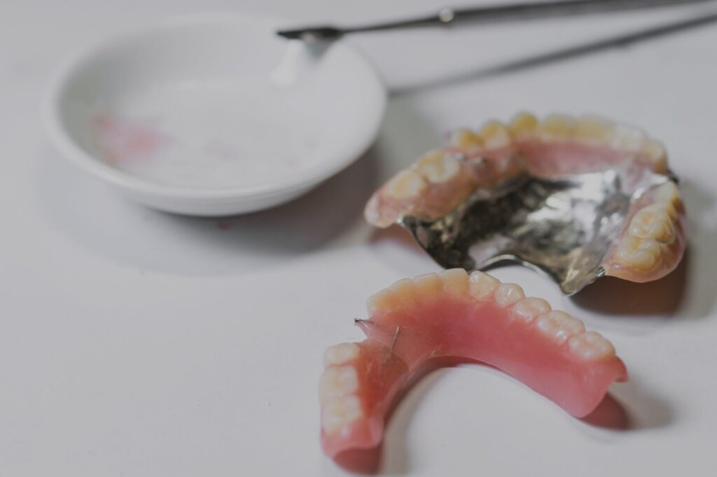 Two dental dentures and dental tools on a white surface.